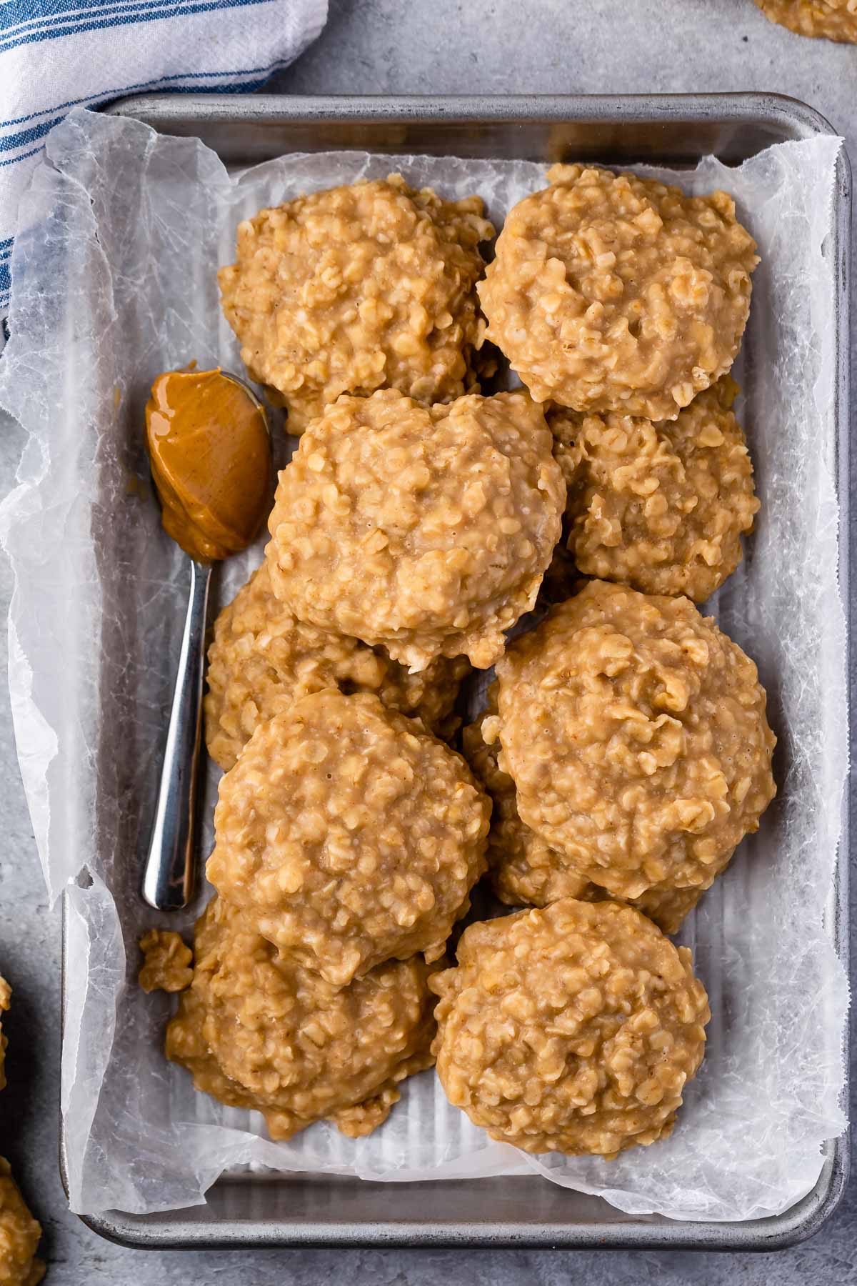 Peanut butter no bake cookies on parchment paper next to a spoonful of peanut butter