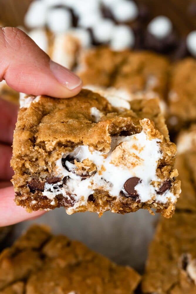 Hand holding one square of oatmeal cookie s'mores bar close to camera