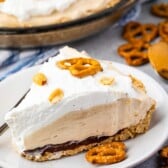 One slice of pretzel peanut butter pie on a plate next to pretzels