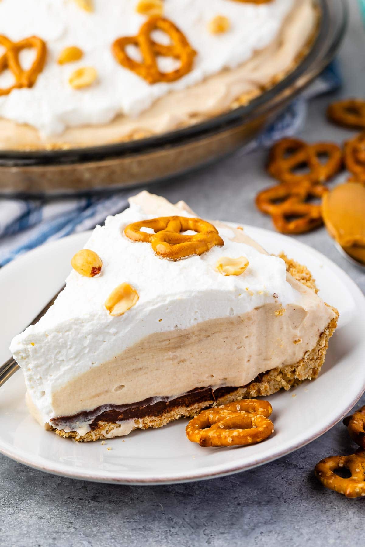 One slice of pretzel peanut butter pie on a plate next to pretzels