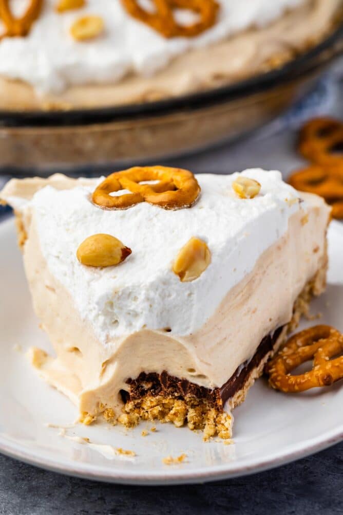 One slice of pretzel peanut butter pie on a plate with one bite missing