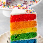 slice of rainbow cake on white plate with words on photo