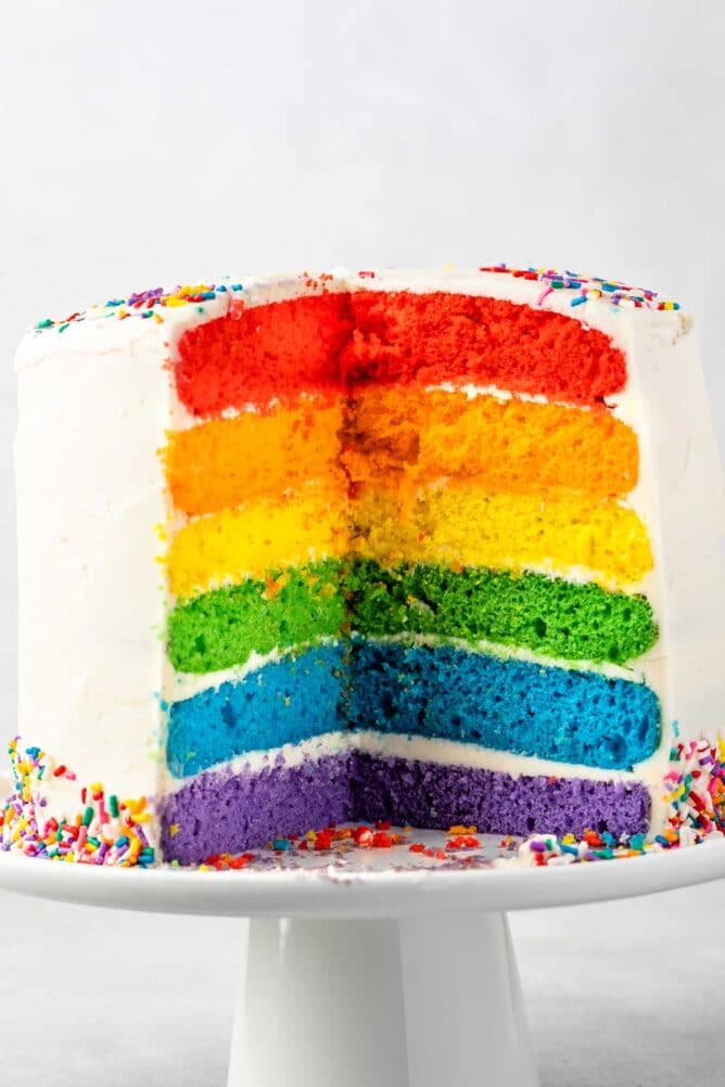 cut open rainbow cake on white cake plate