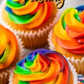 Overhead shot of rainbow swirl frosting on top of vanilla cupcakes with recipe title on top of image