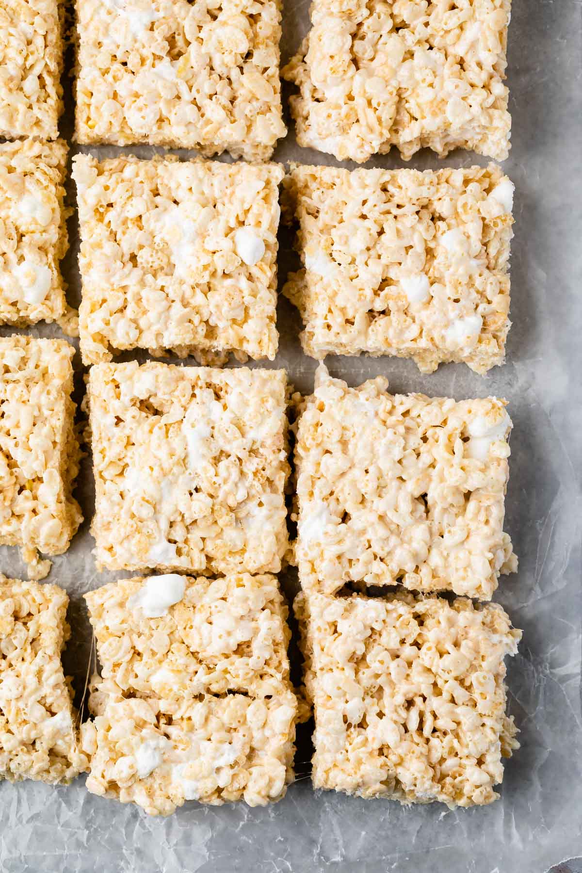 Overhead shot of rice krispie treats cut into squares on parchment paper