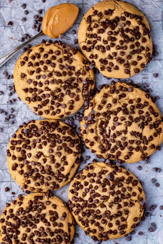 Overhead shot of ultimate stuffed peanut butter cookies on parchment paper surrounded by mini chocolate chips