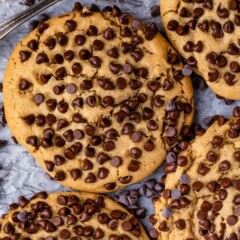 Close up overhead shot of ultimate stuffed peanut butter cookies on parchment paper surrounded by mini chocolate chips