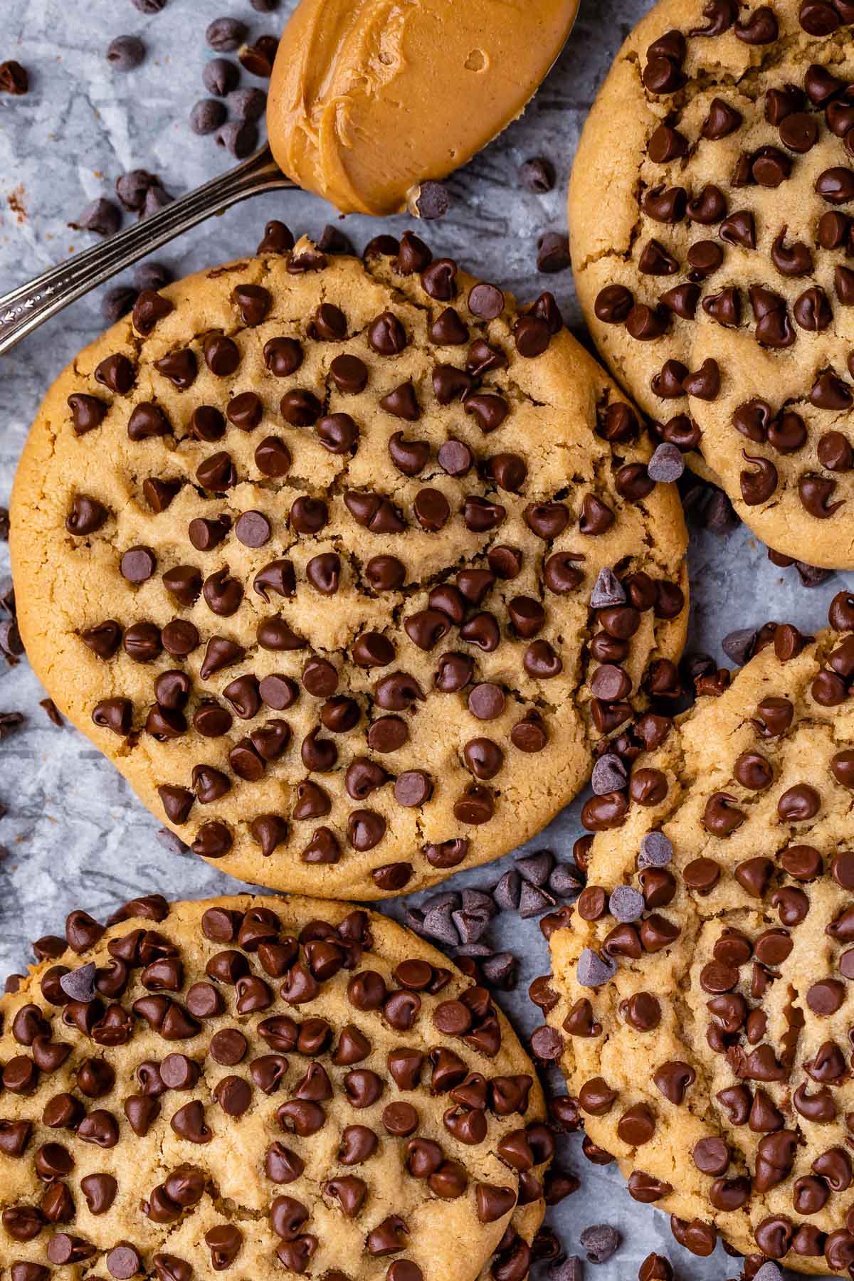 Close up overhead shot of ultimate stuffed peanut butter cookies on parchment paper surrounded by mini chocolate chips