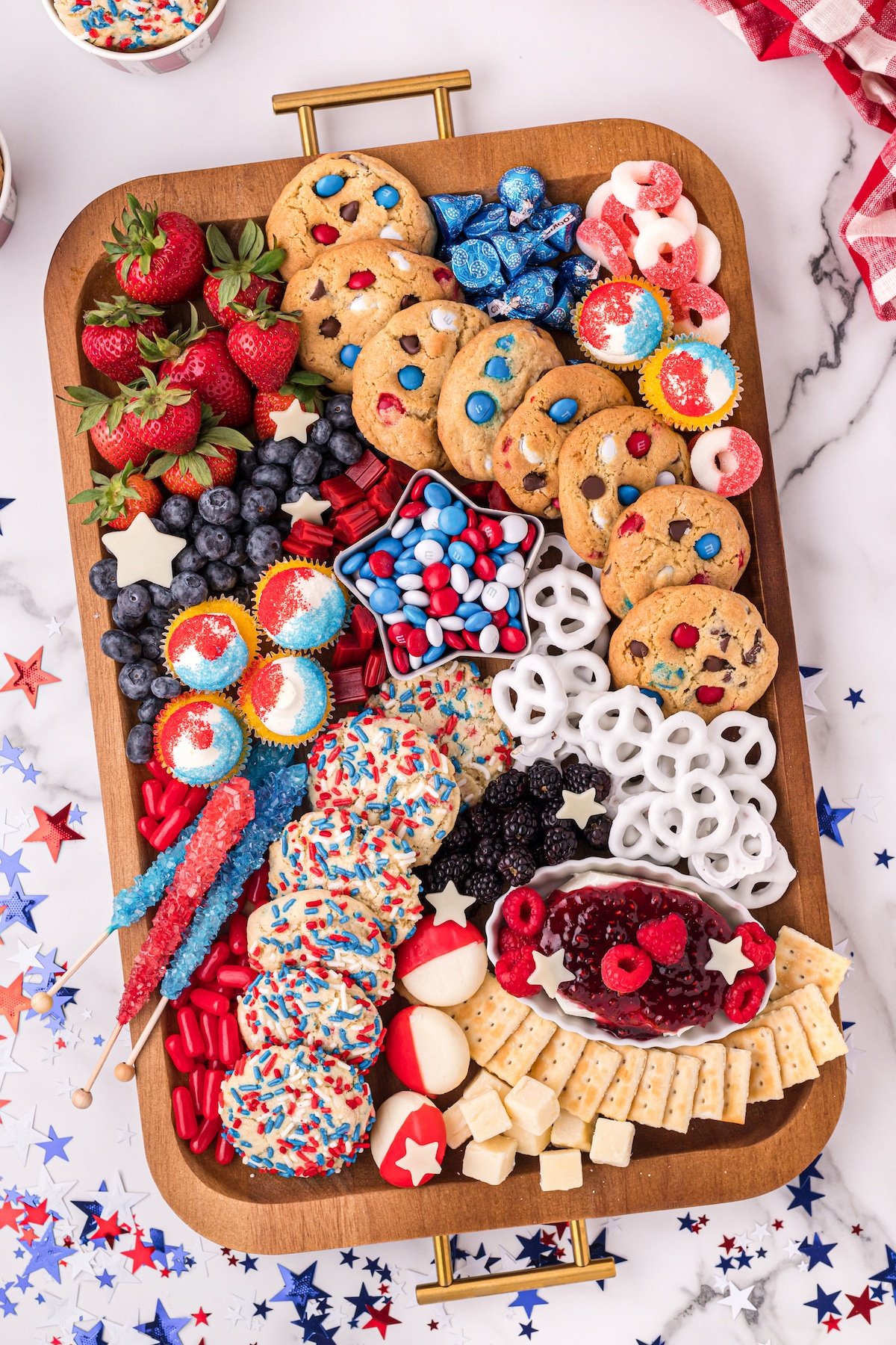 Overhead shot of 4th of july dessert board filled with red, white and blue snacks on a festive table