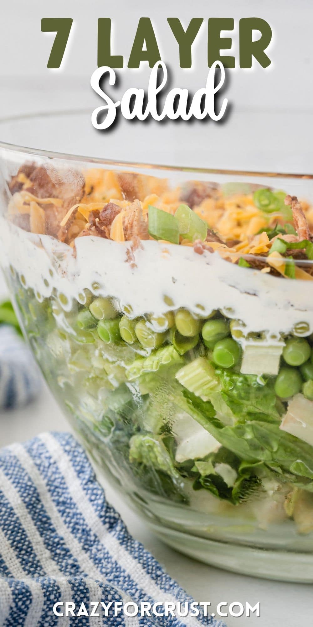 layered salad in a clear bowl showing lettuce and dressing and meat and cheese with words on the photo