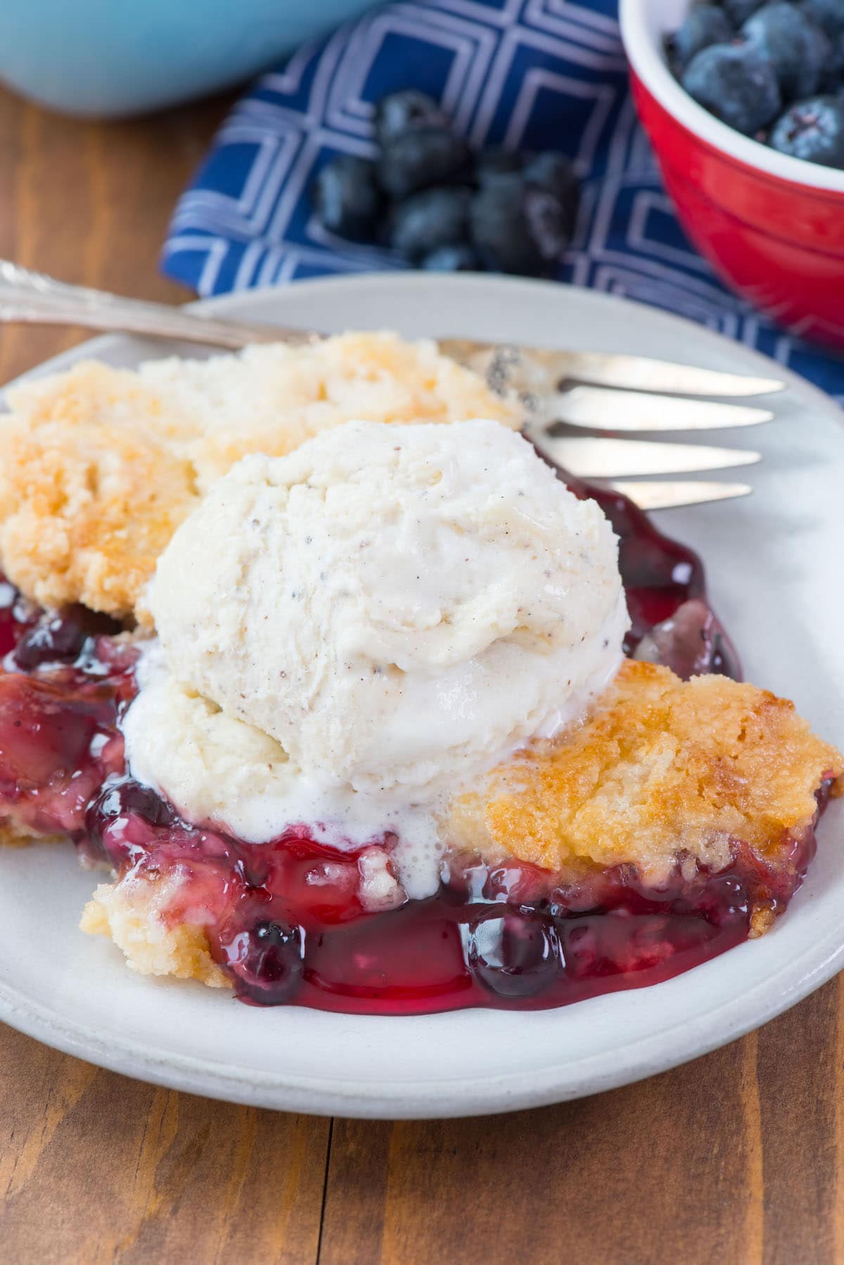berry dump on a white plate with vanilla ice cream on top