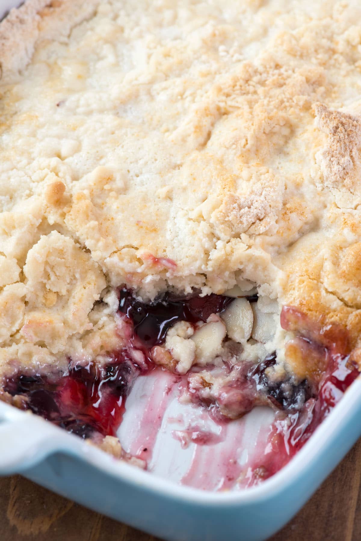 full berry cake in a teal pan with a slice taken out of the pan