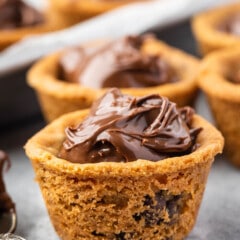 one Nutella cup with a spoonful of Nutella sitting next to it