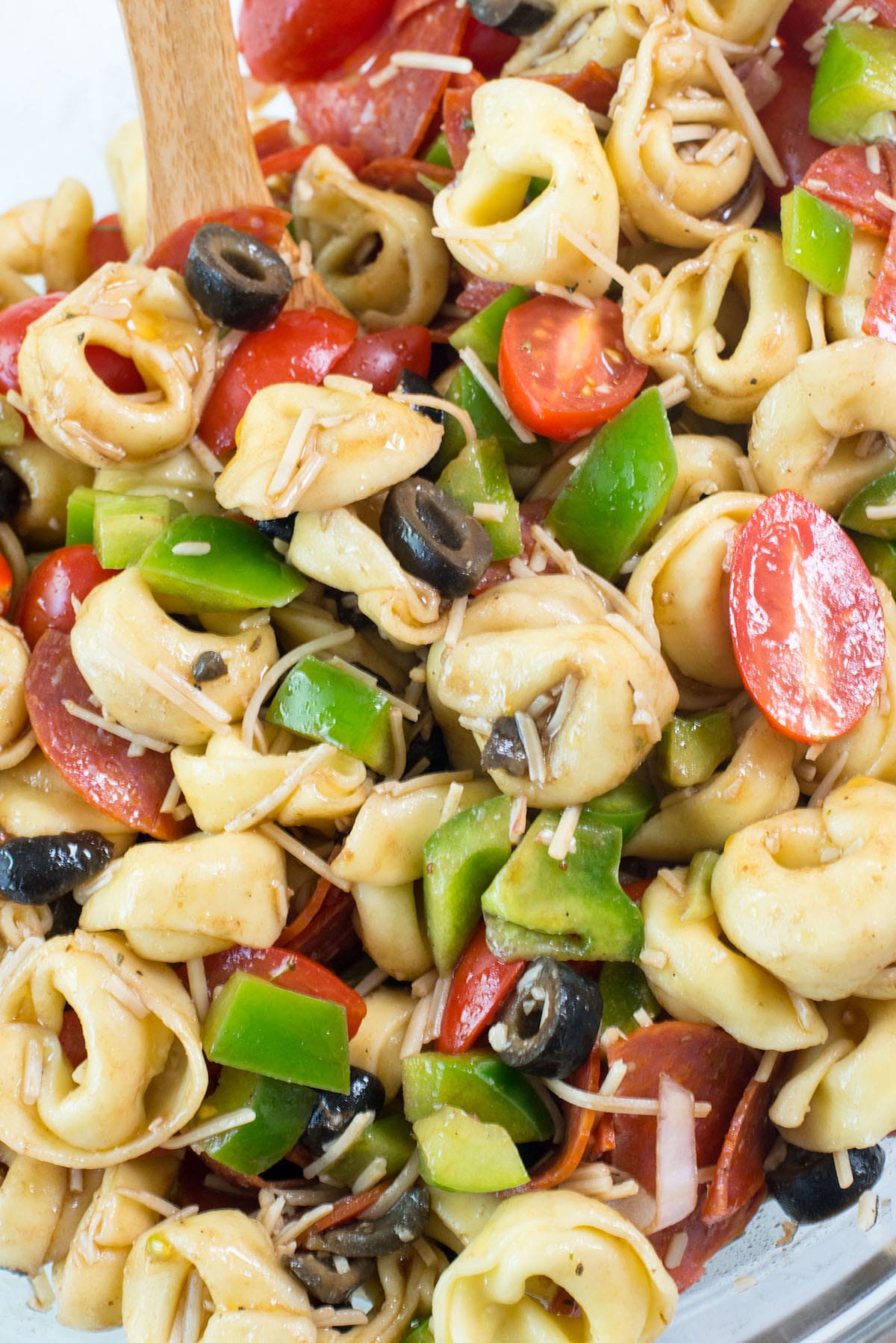 tortellini and tomatoes and pepperoni and peppers mixed in a clear bowl