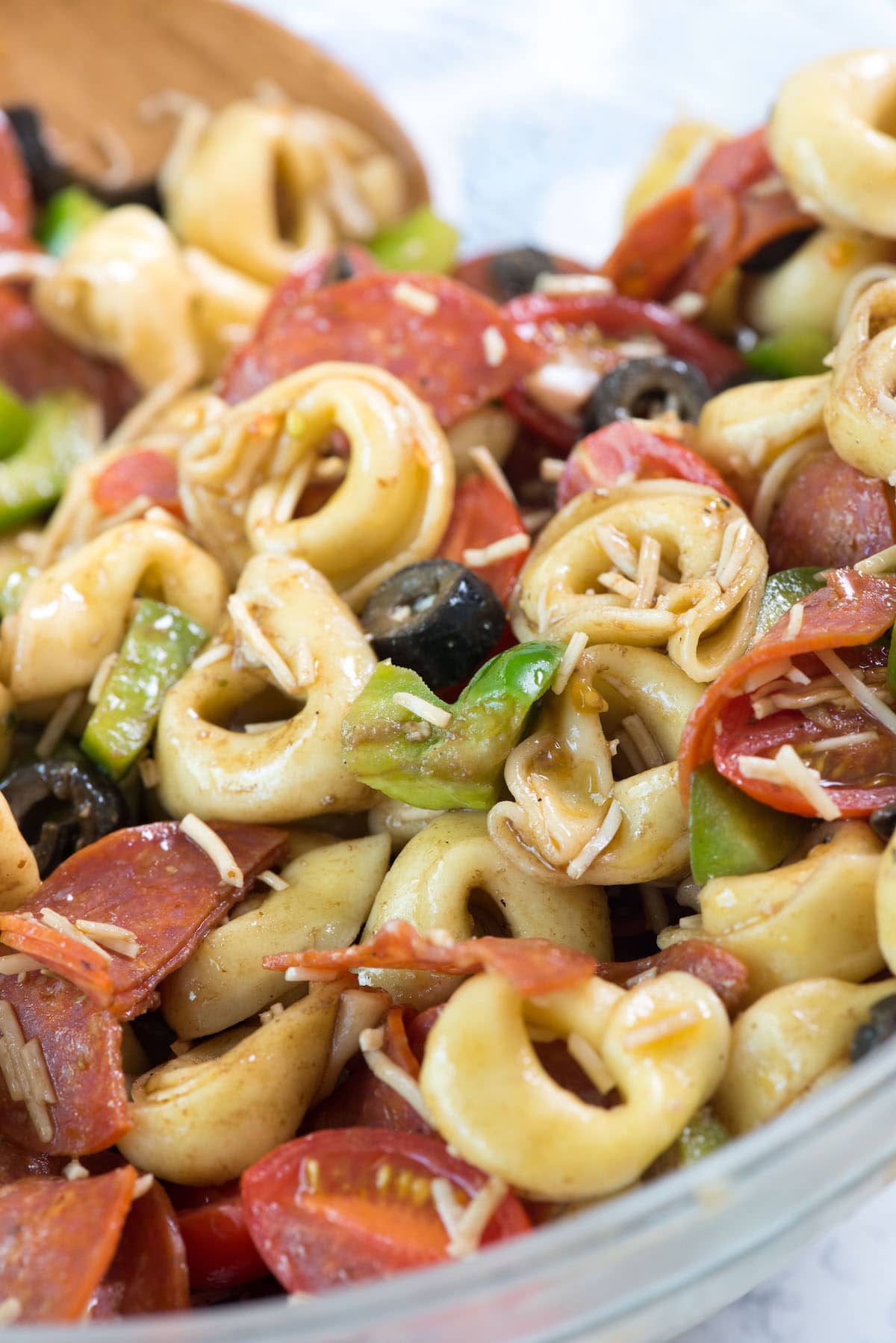 tortellini and tomatoes and pepperoni and peppers mixed in a clear bowl