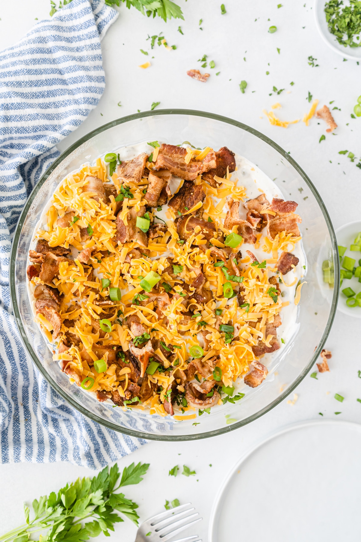 overhead shot of meat and cheese on top of the salad in a clear bowl