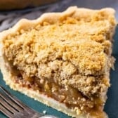 one slice of apple pie on a dark green plate with crumble topping and words on the photo