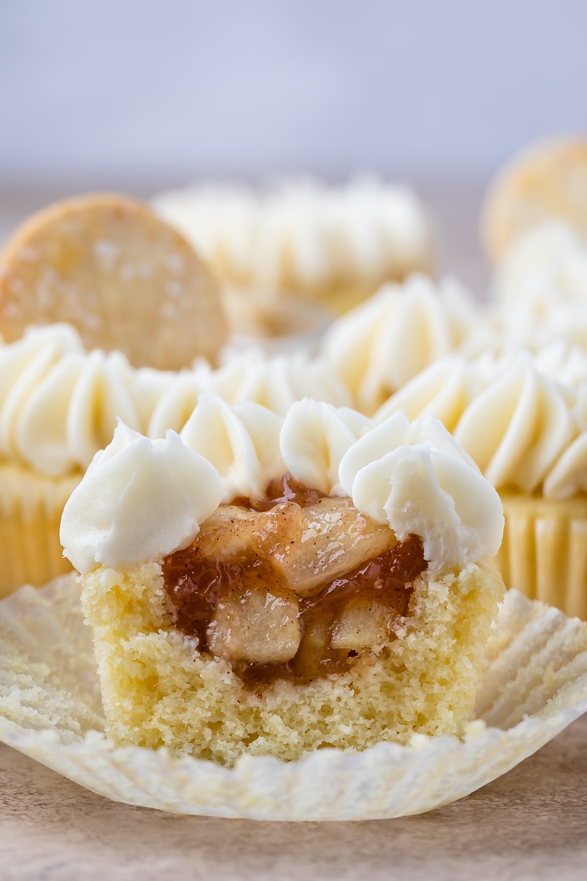 cupcake with white frosting cut in half to show apple filling