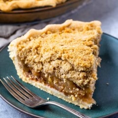one slice of apple pie on a dark green plate with crumble topping