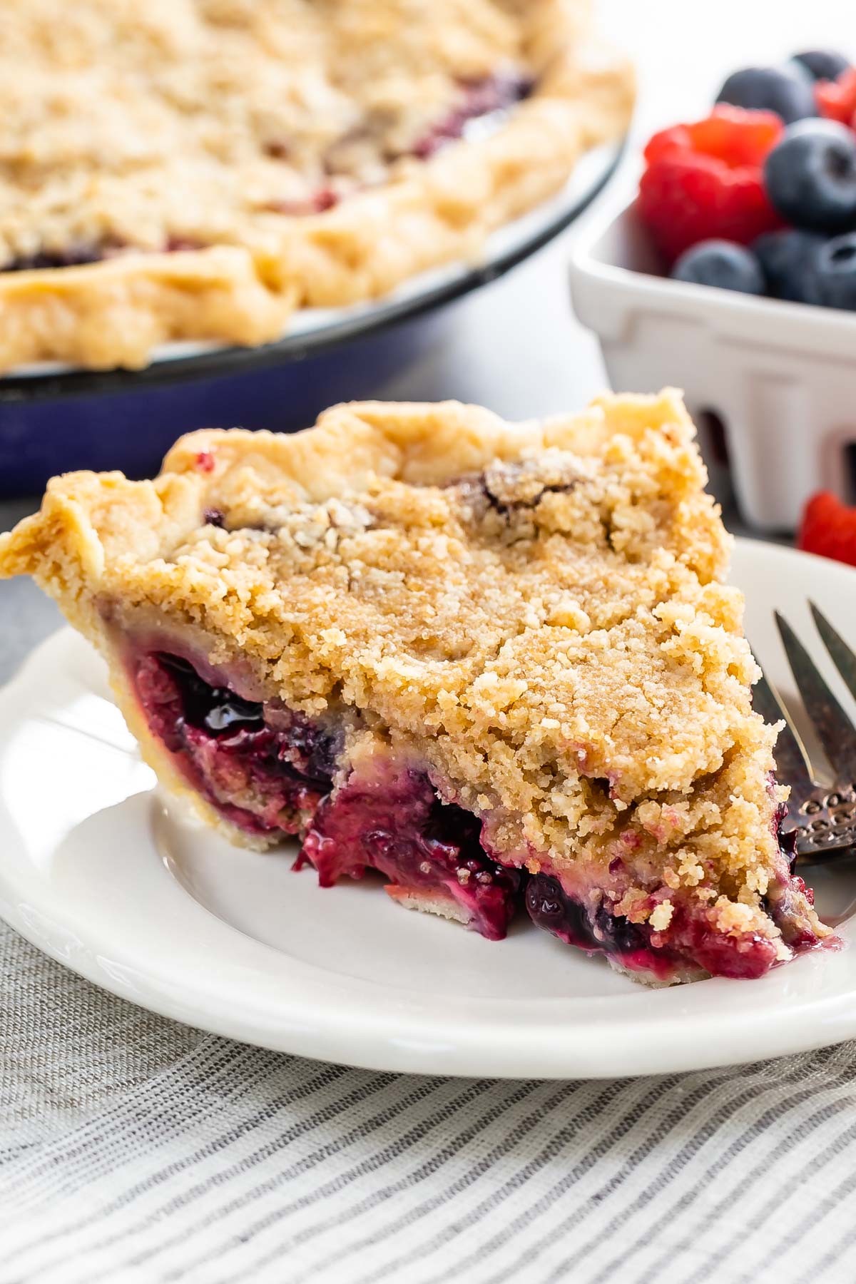 One slice of mixed berry pie on a plate with fork