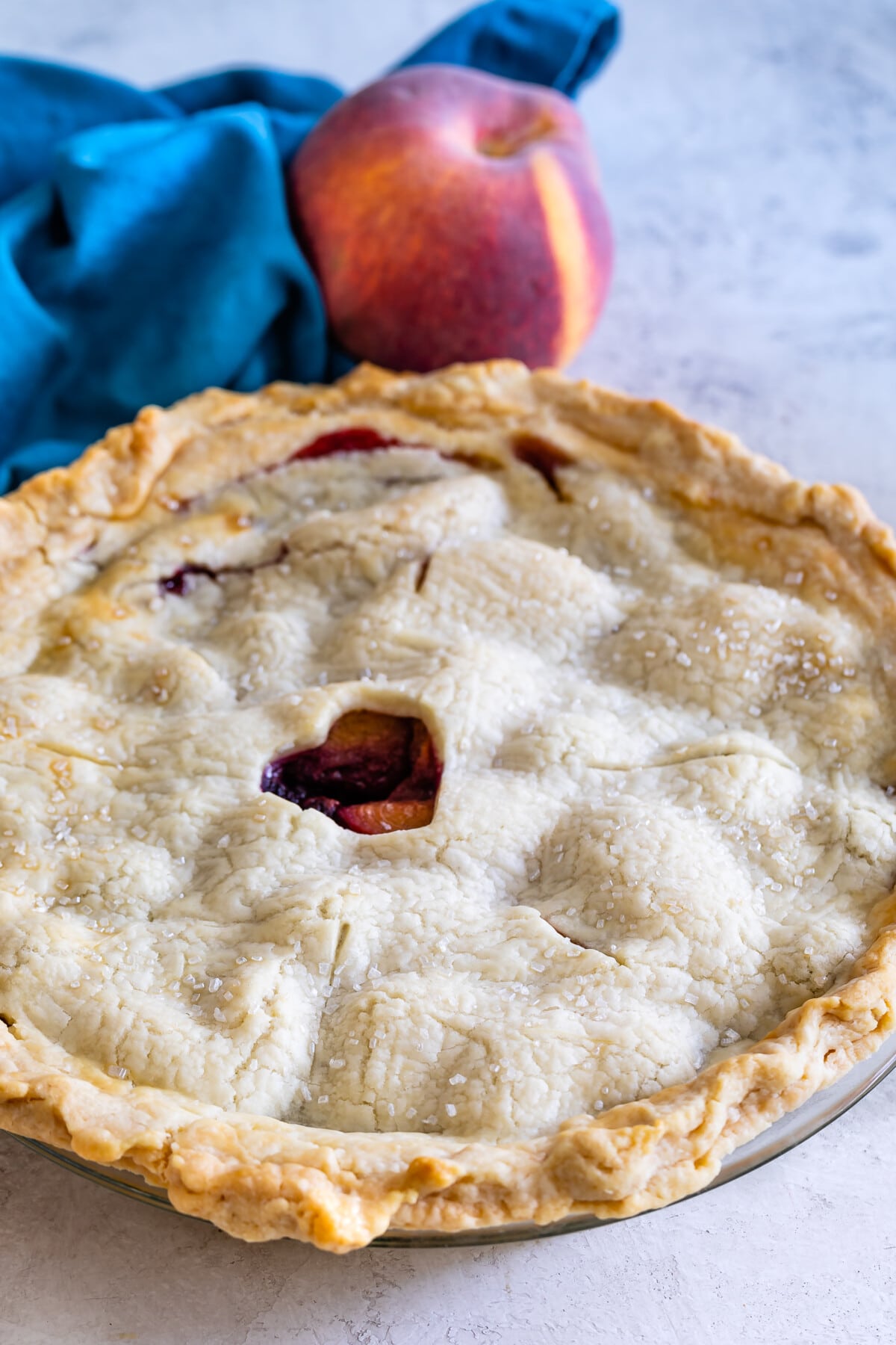 full pie with a heart cutout in the center and a peach in the background