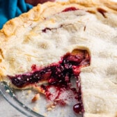 full pie with a slice taken out of it in a clear pie pan