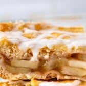 two slices of apple pie with frosting on top sitting on a light grey plate with words on the photo