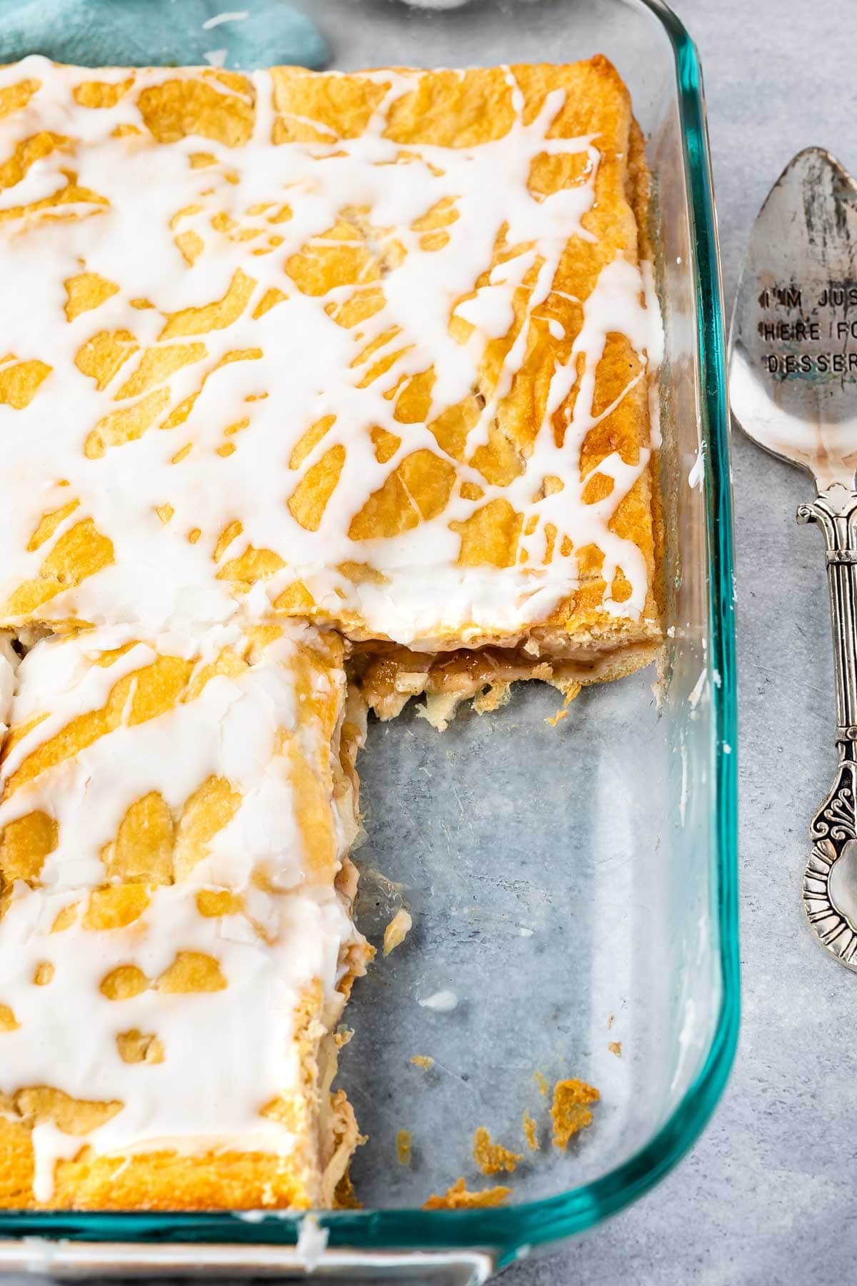 overhead shot of cake in a clear pan with frosting on top and two slices have been removed