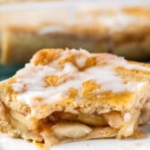 one slice of pie on a light grey plate with frosting on top