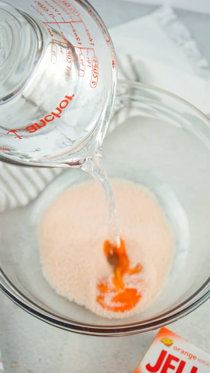 Vodka being poured into orange jello mixture