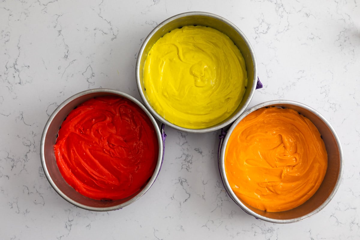 cake pans with food colored cake batter in them