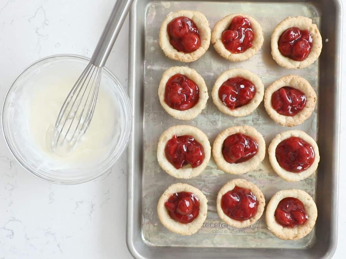 cookie cups on cookie sheet with bowl of icing