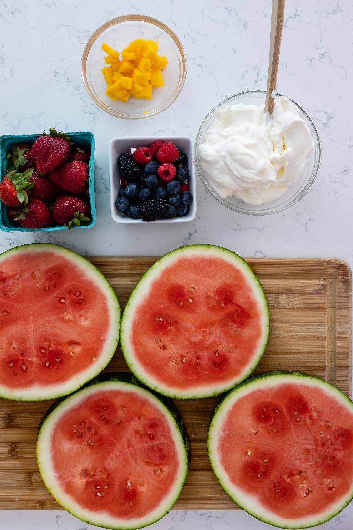 slices of watermelon, berries, mango and whipped cream