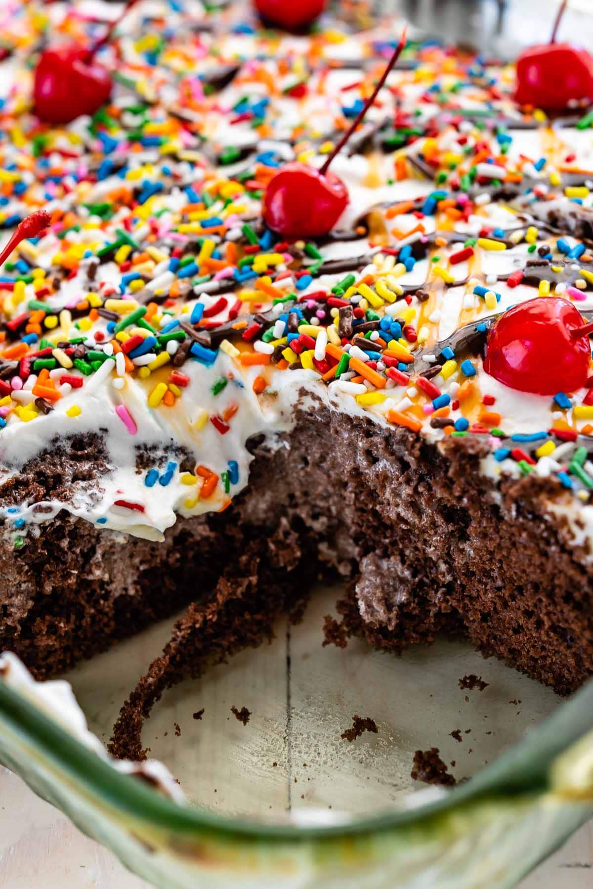 full poke cake in a clear pan with a slice taken out