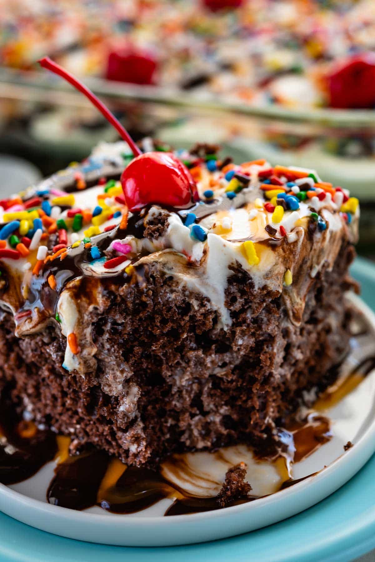 slice of poke cake with cherry and frosting on top sitting on a white plate