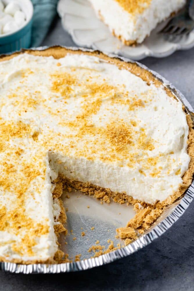 Marshmallow pie topped with graham cracker crumbs with one slice of pie missing