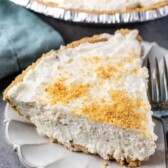 One slice of marshmallow pie on a scalloped plate next to a fork