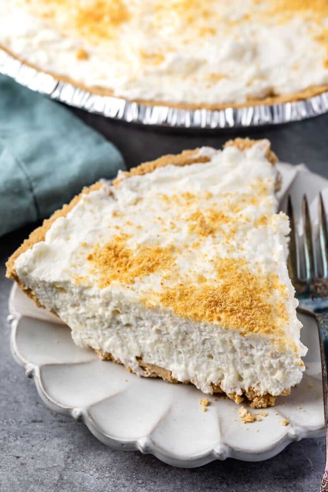 One slice of marshmallow pie on a scalloped plate next to a fork