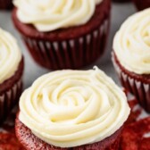 Red velvet cupcakes topped with cream cheese frosting and recipe title on top of photo