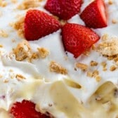 shortcake in a clear pan with four sliced strawberries in the center and a piece taken out of the corner with words on the photo