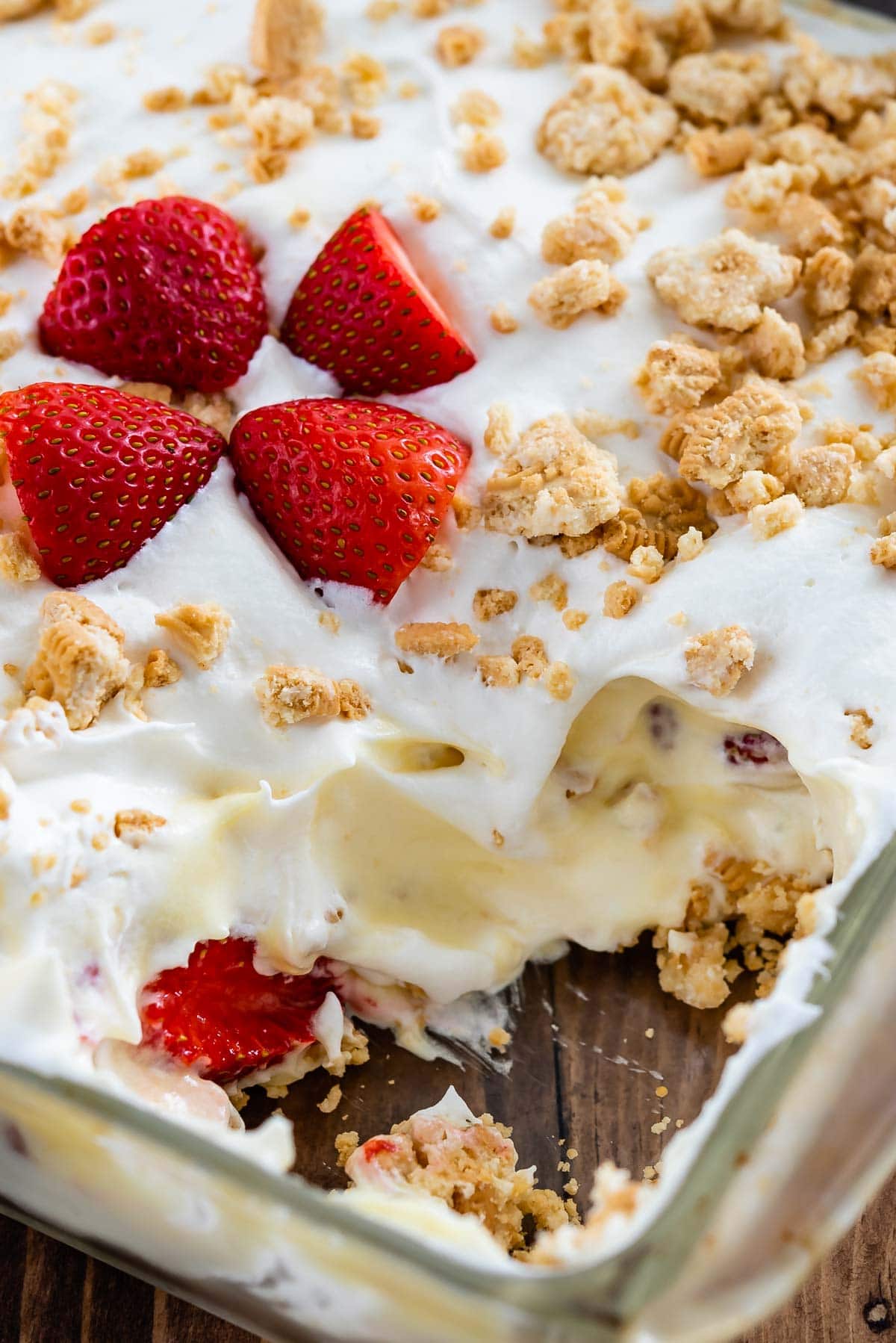 shortcake in a clear pan with four sliced strawberries in the center and a piece taken out of the corner