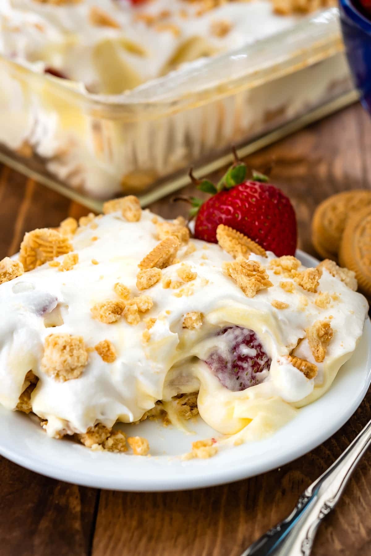 slice of shortcake on a white plate with a strawberry behind it