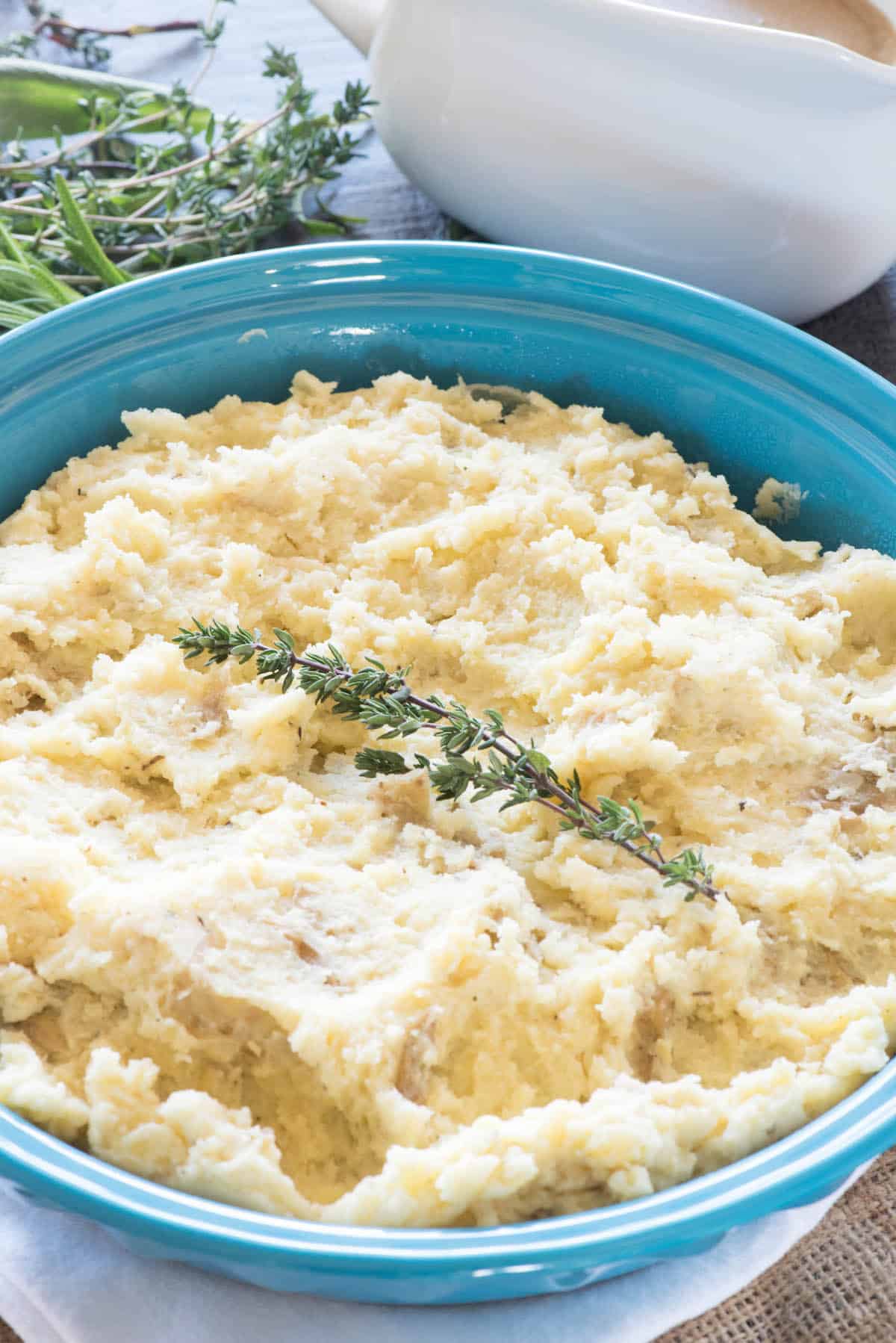 mashed potatoes in a teal blue pan and herbs on top