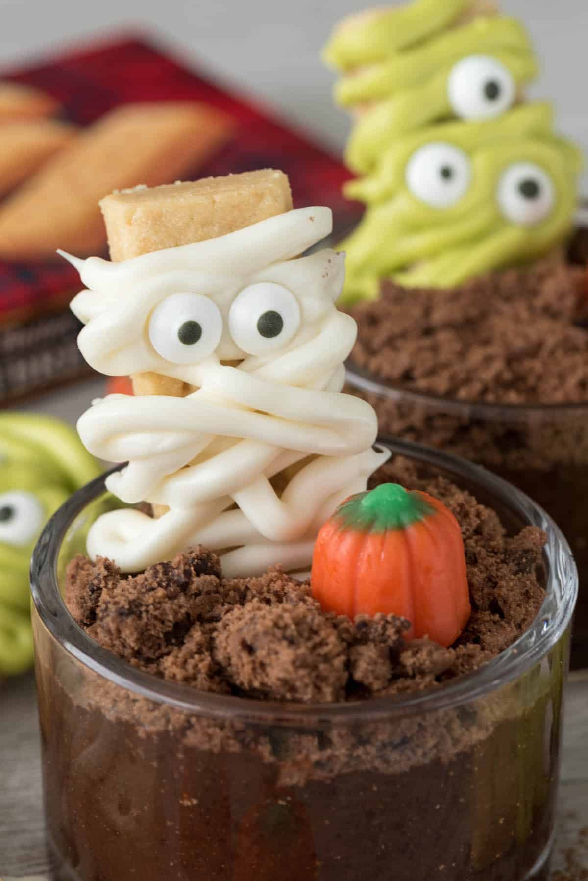 mummy decorated cookie in a dirt cup next to a candy corn pumpkin