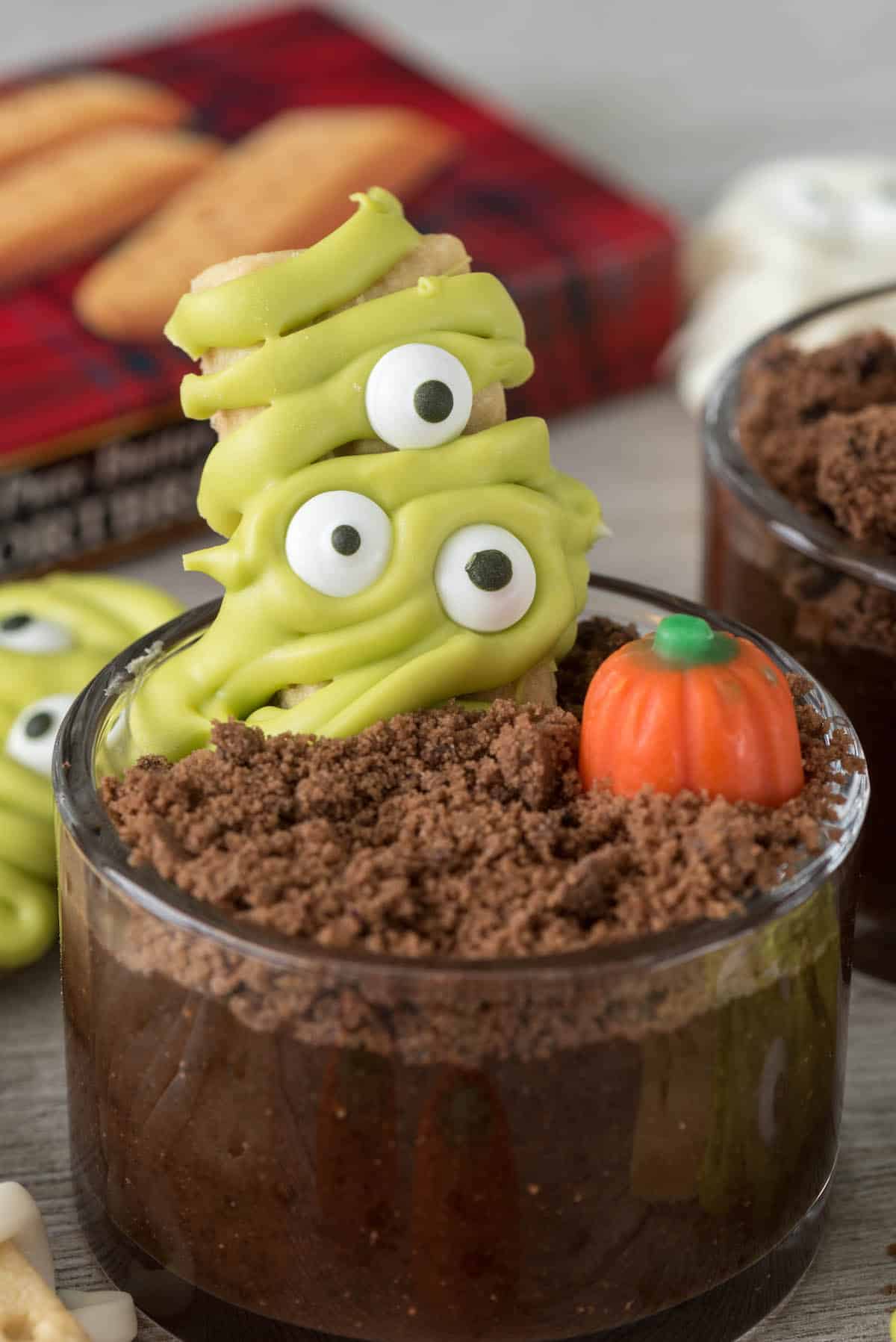 monster decorated cookie in a dirt cup next to a candy corn pumpkin