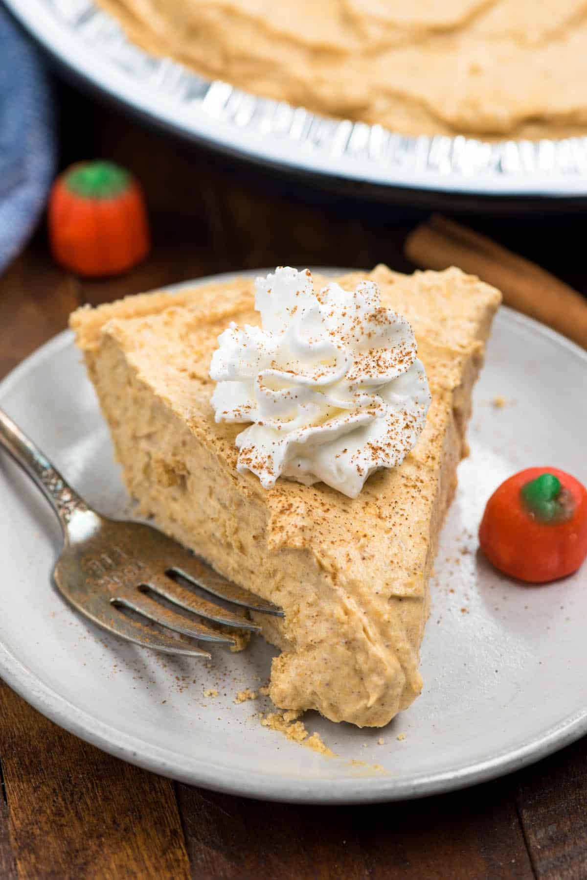 pumpkin pie on a grey plate with a fork next to it