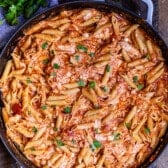 pasta mixed with herbs and sauce in a black pan