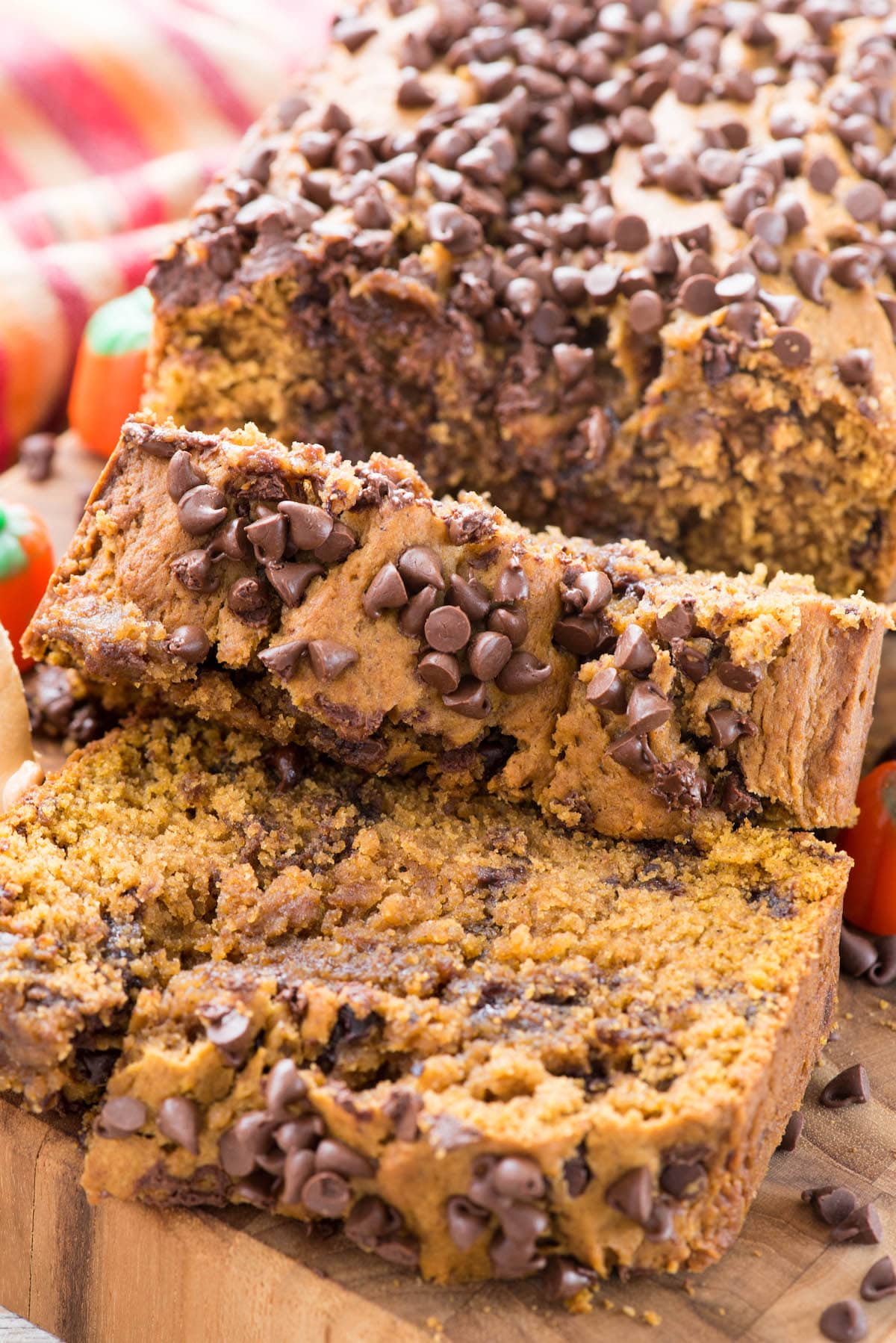 close up photo of loaf of pumpkin quick bread with chocolate chips, 2 slices laying on cutting board