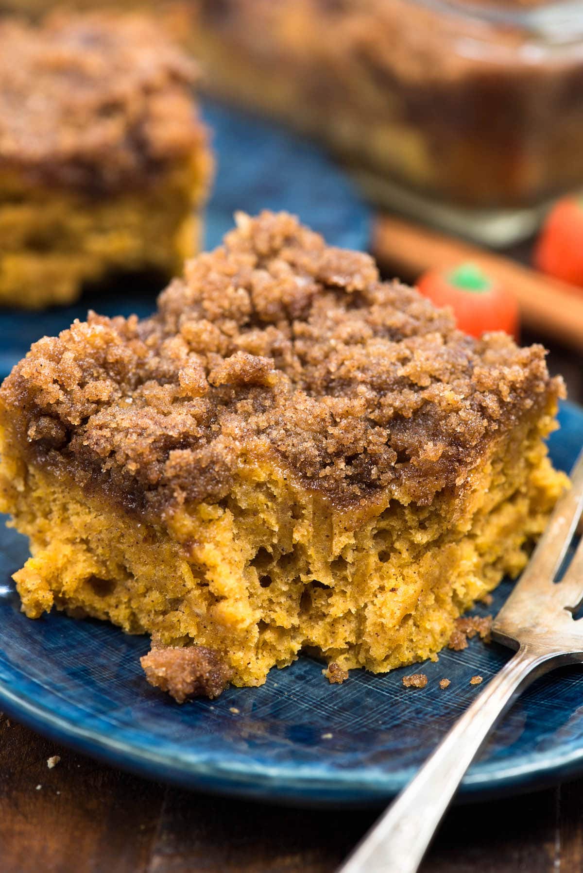 coffee cake on a dark blue plate next to a fork with a bite taken out