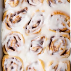 a white pan full of cinnamon rolls with icing on top